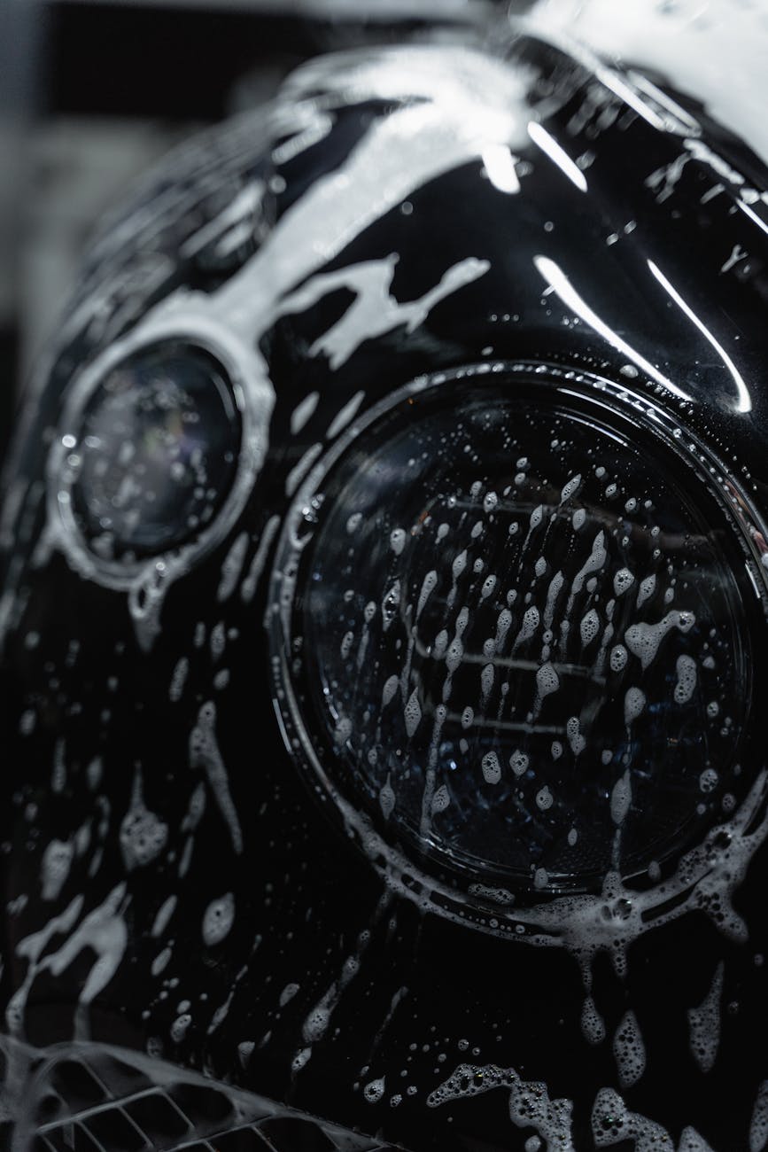 a close up shot of the headlight of a car while being washed